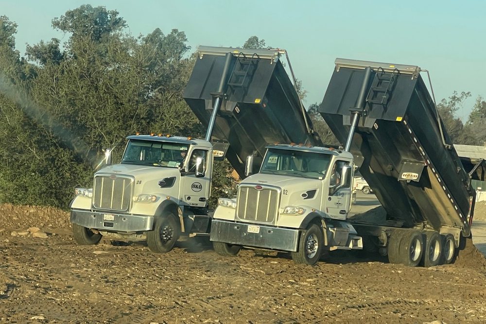 B&D Transportation bottom dump trucks unloading aggregate on a grading site