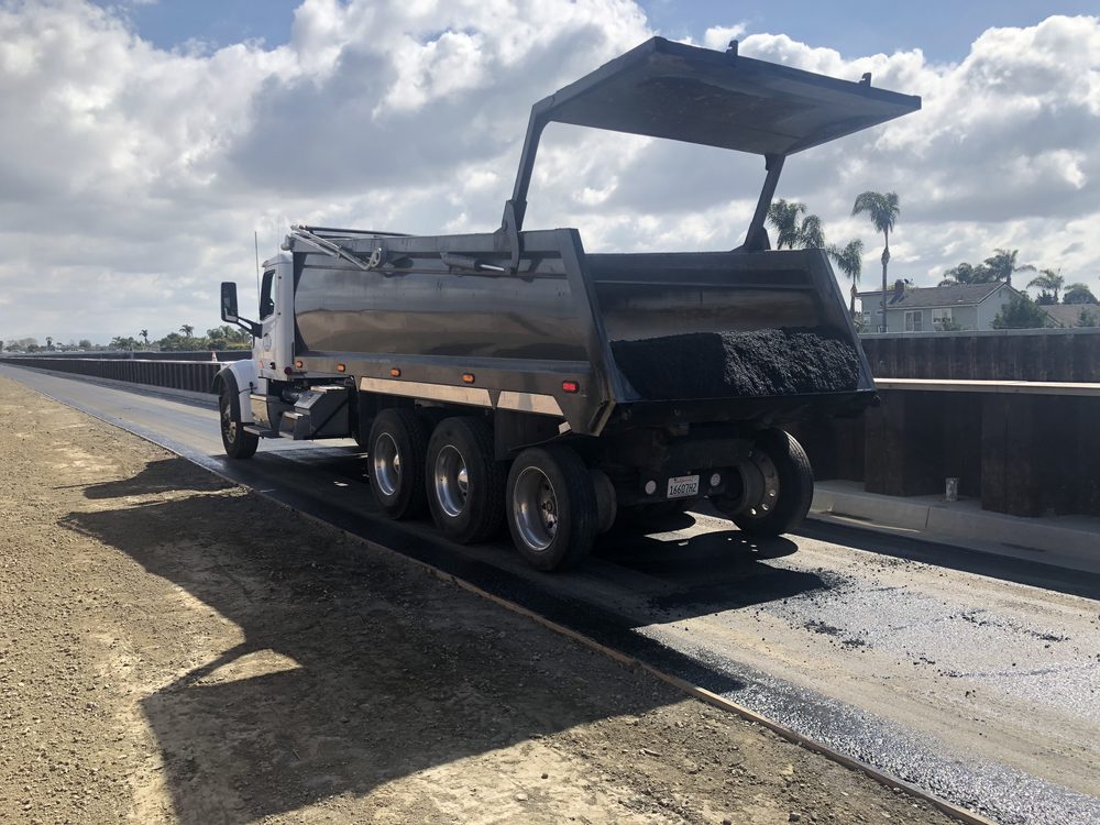 B&D Transportation truck delivering hot mix asphalt to a paving machine
